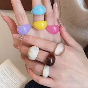Macro view of colorful geometric resin rings with unique marble patterns on model's fingers
