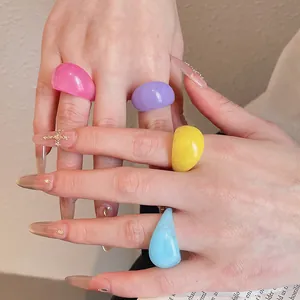 Close-up of vibrant colorful chunky resin rings on hand with decorative nails