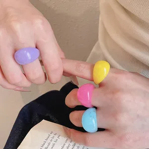 Detailed shot of vibrant multi-color marbled resin geometric rings on a person's hand