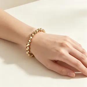 Detailed close-up of a gold-colored faceted pyrite bead bracelet worn on a slender wrist.
