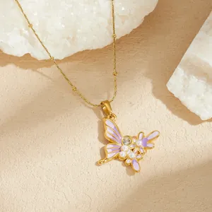 Gros plan d'un collier pendentif papillon doré avec émail violet et perles