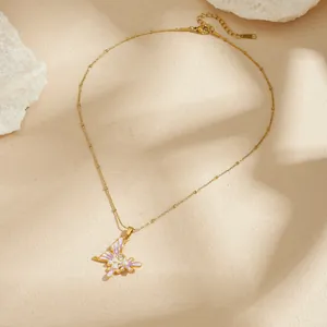 Détail d'un pendentif papillon doré avec émail lilas et perles délicates en nacre