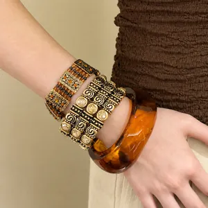 Nahaufnahme eines ethnischen Armband-Sets mit bernsteinfarbenem Armreif und Golddetails.