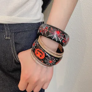 Vista dettagliata di bracciali di Halloween in resina con ragnatele e zucche sul polso.