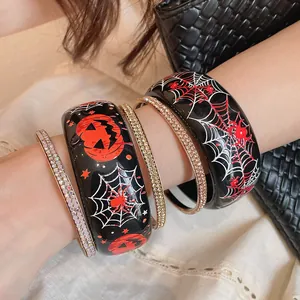 Primo piano di bracciali di Halloween in resina con stampe di zucca e ragnatela.
