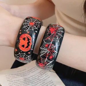 Dettaglio di bracciali spessi in resina con stampe di Halloween, ragnatele e zucche