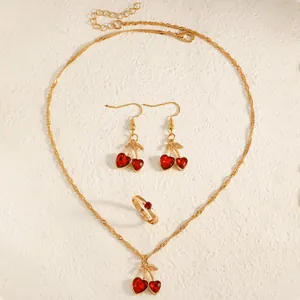 Close-up of vintage gold cherry jewelry set with red heart crystals on textured background