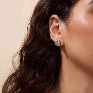 Detailed close-up shot of a minimalist triangle zircon stud earring worn by a female model
