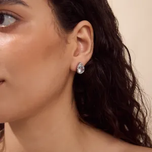 Close-up detail shot of a sparkling pear-shaped zircon stud earring on a model's ear