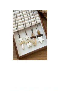 Detail view of boho ethnic long necklaces with stone stars and teardrop pendants in a wooden tray