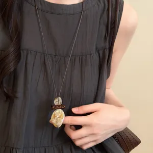 Close-up of retro ethnic long necklace with marbled waterdrop pendant on a woman model