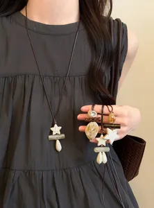 Close-up of bohemian long necklace featuring lucky star and teardrop pendants