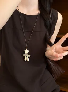 Close-up of a retro ethnic necklace with star and waterdrop pendants worn by a model.