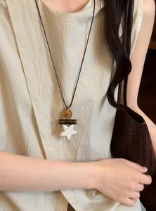 Detailed view of retro ethnic style long necklace with a white star pendant on a model.