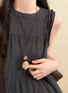 Macro view of retro ethnic long necklace featuring waterdrop pendant worn by model