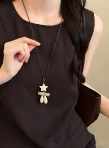 Close-up of a retro ethnic style long necklace with star and water-drop pendants on a model.