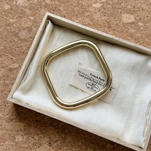 Détail d'un bracelet jonc carré doré dans un coffret cadeau en bois rustique