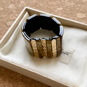 Vue macro d'un bracelet bohème en acrylique avec des touches d'écaille et d'or.