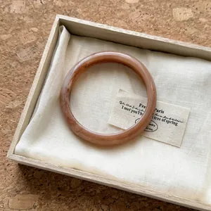 Gros plan d'un bracelet en acrylique ambré avec texture marbrée dans sa boîte