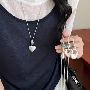 Collier pendentif minimaliste en argent brossé avec cœur et perles turquoises sur un modèle