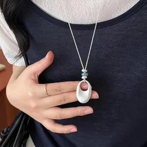 Collier avec pendentif ovale géométrique brossé de style coréen porté par un modèle