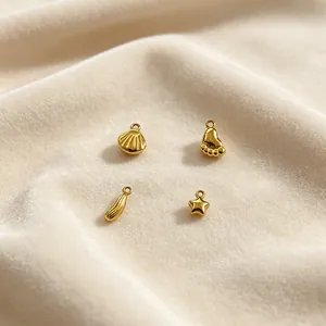 Nahaufnahme goldener Edelstahl-Anhänger: Muschel, Fuß und Stern für DIY-Schmuck