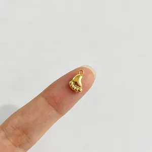Makro-Detail eines goldenen Babyfuß-Edelstahlanhängers auf einem Finger zum Größenvergleich.