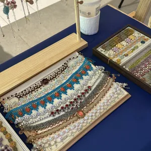 Variety of handmade beaded resin flower bracelets displayed in wooden jewelry trays