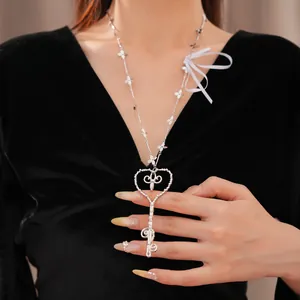 Primer plano de un collar con colgante de llave de corazón y cadena floral en vestido negro