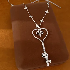 Vista detallada de un collar de llave de corazón de plata con perlas y flores finas