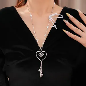 Detalle de un elegante collar de perlas con corazón y llave sobre terciopelo negro.