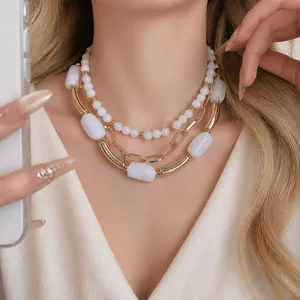 Elegante collana a strati in oro e perle acriliche bianche indossata da modella