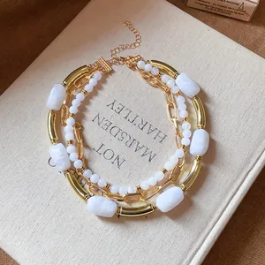 Dettaglio della collana multistrato con perle acriliche marmorizzate e tubi oro.