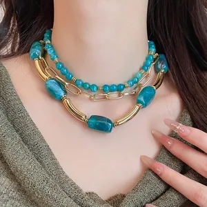 Dettaglio ravvicinato di una collana multistrato con perline acriliche verde foglia e oro