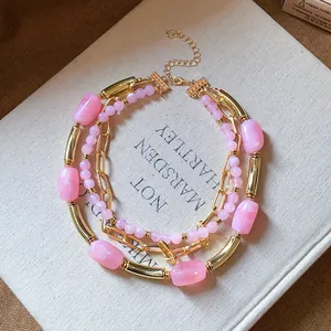 Dettaglio raffinato di una collana multistrato con perle rosa e catena dorata su un libro