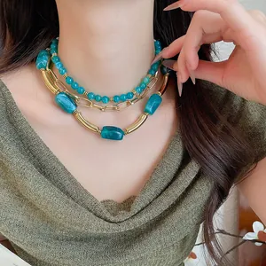 Vista dettagliata di una collana a più strati con perle acriliche verde acqua e catena dorata