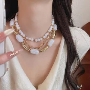 Vista dettagliata di una collana a strati alla moda con perle bianche e oro.