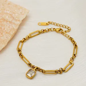 Detail view of gold paperclip link bracelet with a square zircon pendant.