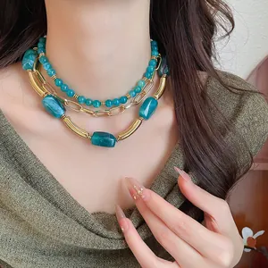 Vista dettagliata di una collana a strati con perle acriliche verde acqua e catena dorata