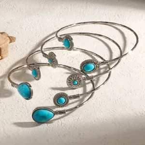 Gros plan de bracelets ethniques vintage sertis de turquoises dans un design ouvert argenté.