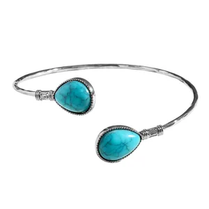 Gros plan d'un bracelet jonc vintage en argent avec deux pierres turquoises en goutte.