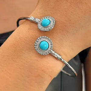 Vue détaillée d'un jonc argenté avec des incrustations de turquoise ronde sur un poignet.