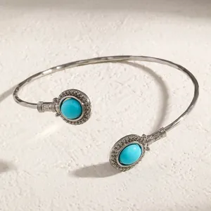 Détail d'un bracelet jonc vintage en argent avec pierres turquoises et bande texturée.