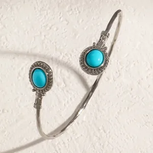 Détail d'un bracelet jonc argenté avec des pierres turquoises rondes de style ethnique.