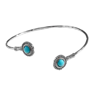 Détail d'un bracelet jonc vintage en argent orné de deux turquoises circulaires.