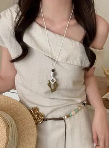 Close-up detail of a vintage style long geometric pendant necklace worn by a model