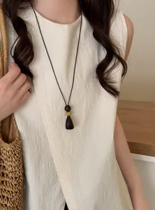 Detail view of a long wooden pendant necklace in retro New Chinese style on linen top