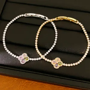 Detailopname van zilveren en gouden klavertje vier armbanden met kleurrijke zirkoon
