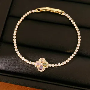 Gedetailleerde close-up van een gouden klaverarmband met veelkleurige zirkonia steentjes.