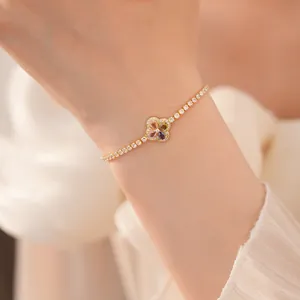 Detailweergave van een luxe vergulde klaverarmband met kleurrijke zirkonia-stenen om de pols